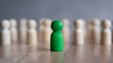A,Green,Wooden,Peg,Doll,Stands,Out,From,A,Group